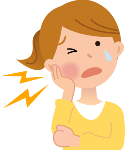 歯が腫れて痛みが出ている女性が頬を抑えているところ